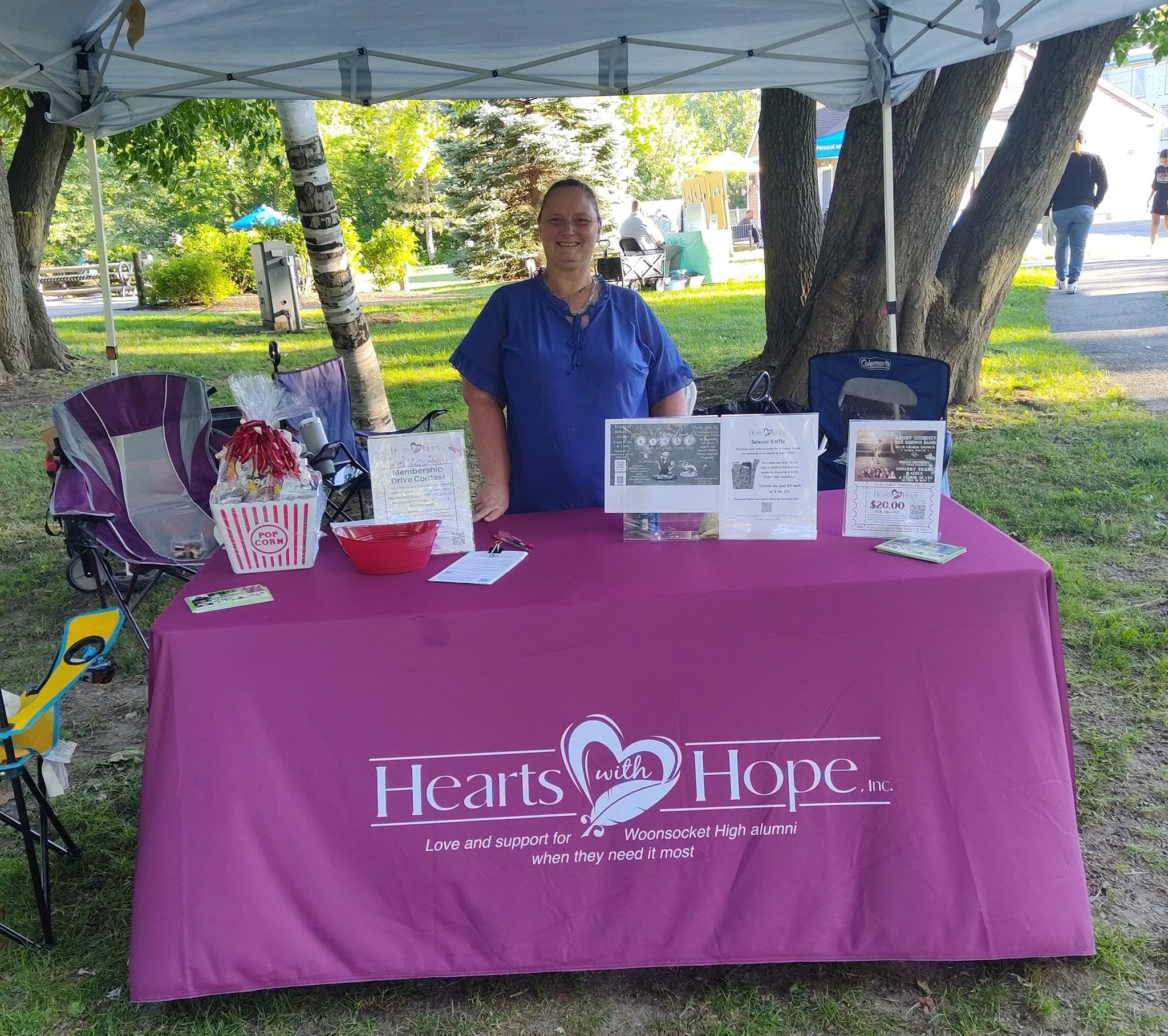 Hearts with Hope member at branded table booth under canopy at outdoor park event