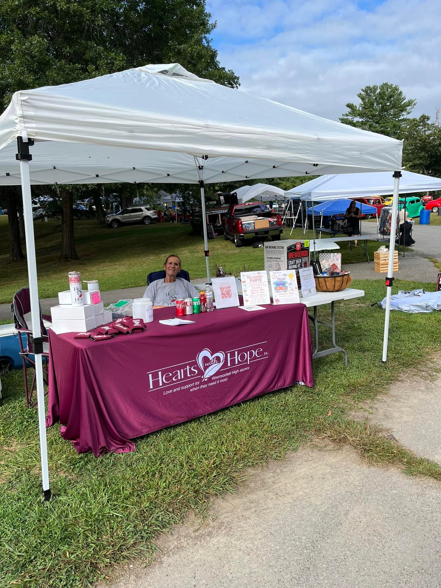 Hearts with Hope member seated at branded table under white canopy tent