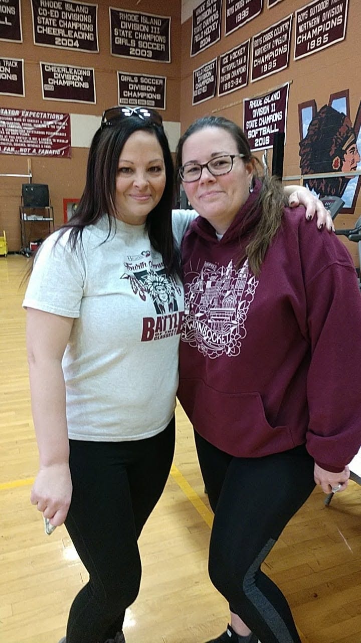 Two people posing together in Woonsocket High School gymnasium