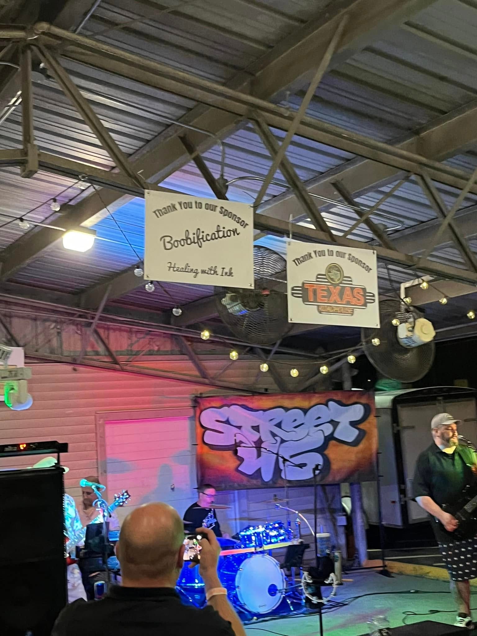 Indoor event venue with stage, lighting, and sponsor banners