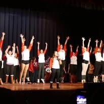 Performers on stage with arms raised at a Hearts with Hope event
