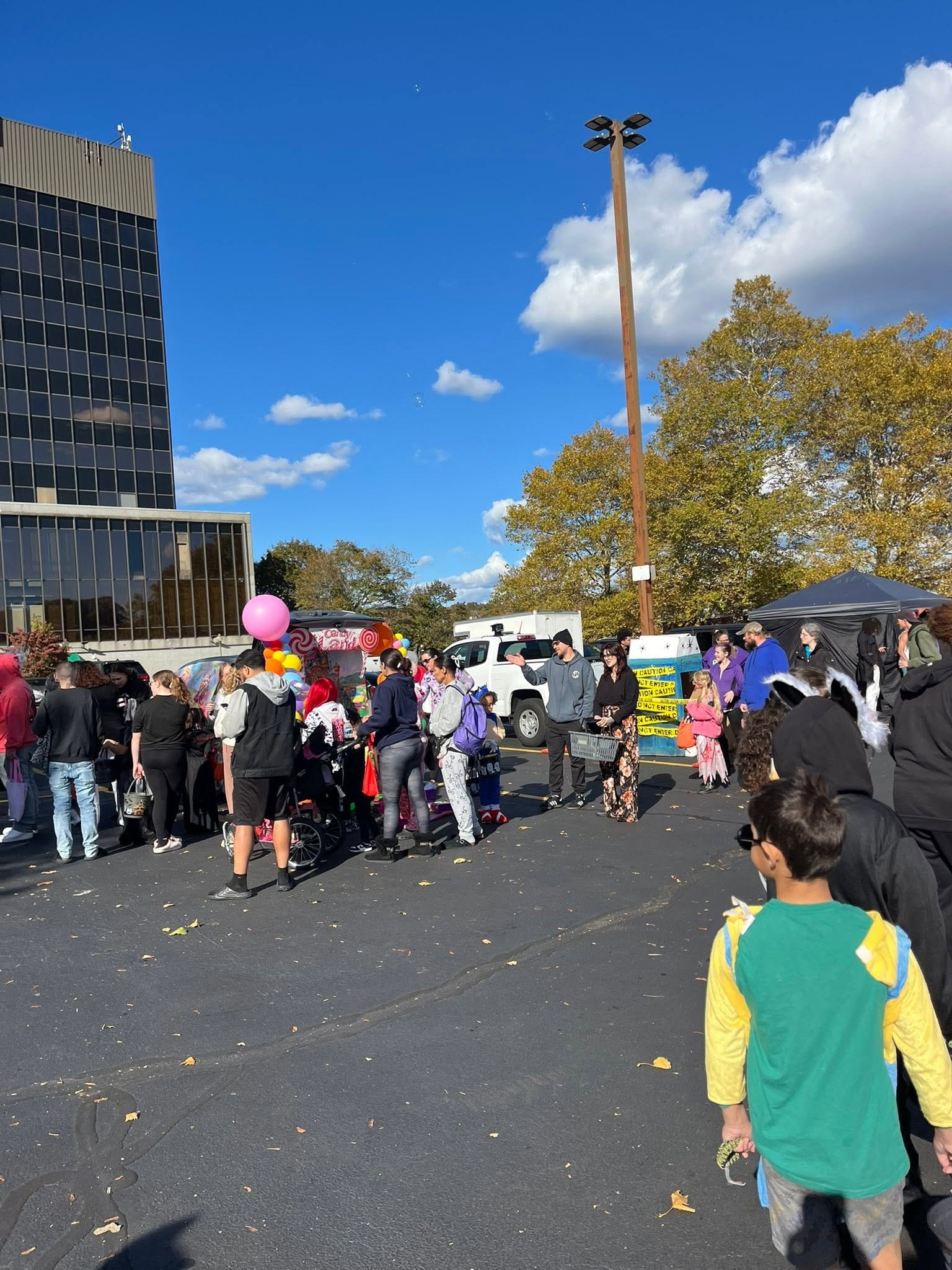 Families in costumes enjoying the Hearts with Hope Trunk or Treat event in a parking lot